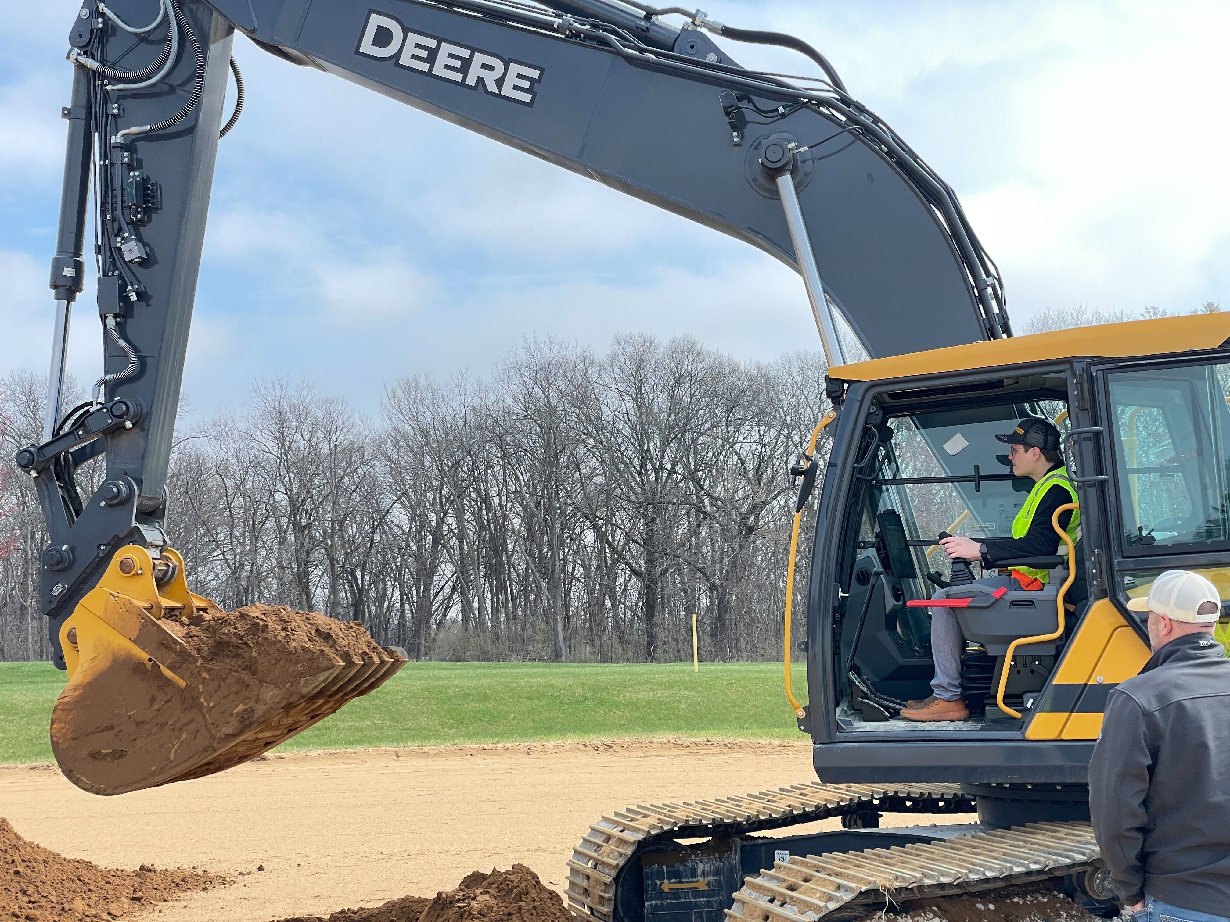 Excavator operator with raised bucket of soil
