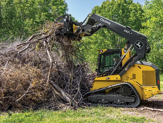 John Deere 333 P-Tier gallery — 333 P-Tier compact track loader using a grapple attachment to clear a pile of branches.